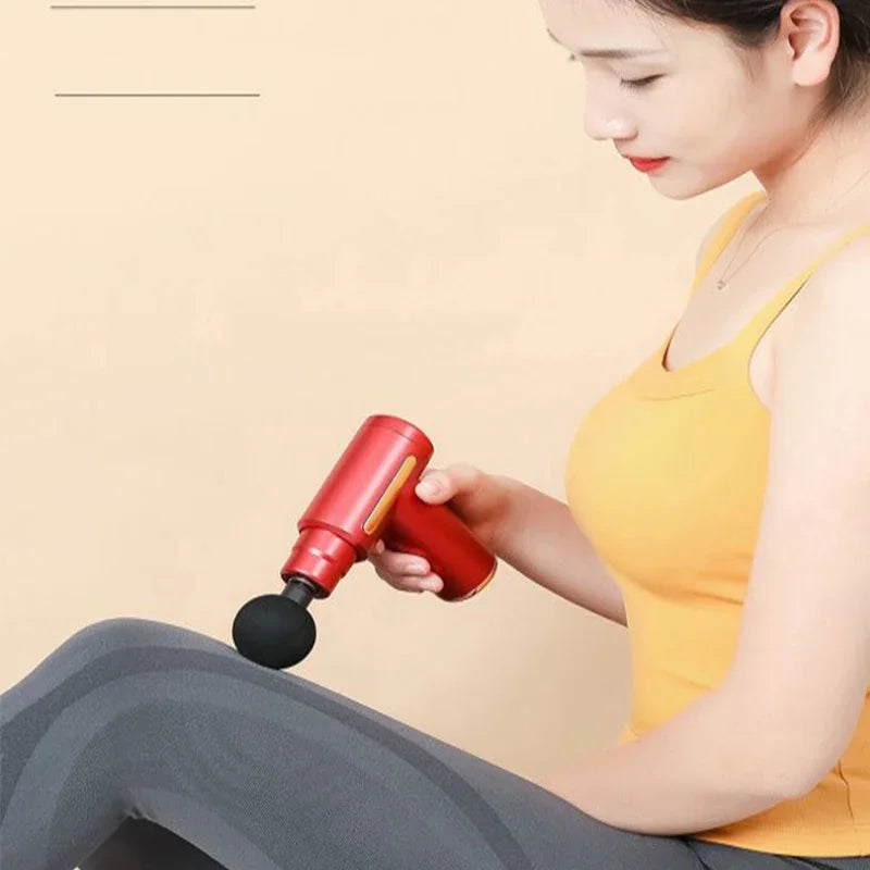 Woman using a red massage gun on her leg against a beige background