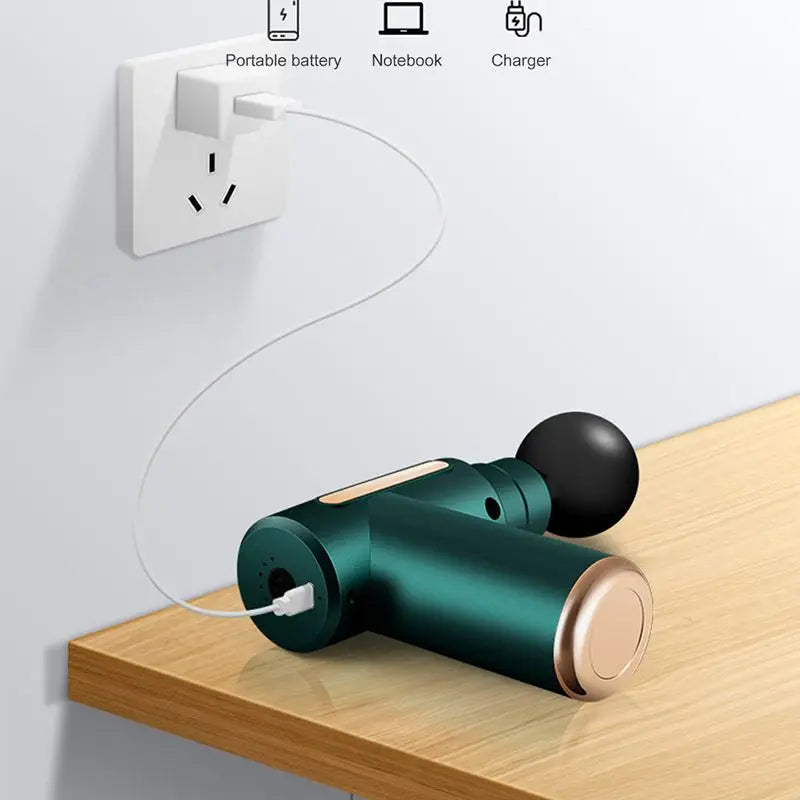 Green portable battery charger on a wooden surface with a power outlet in the background.