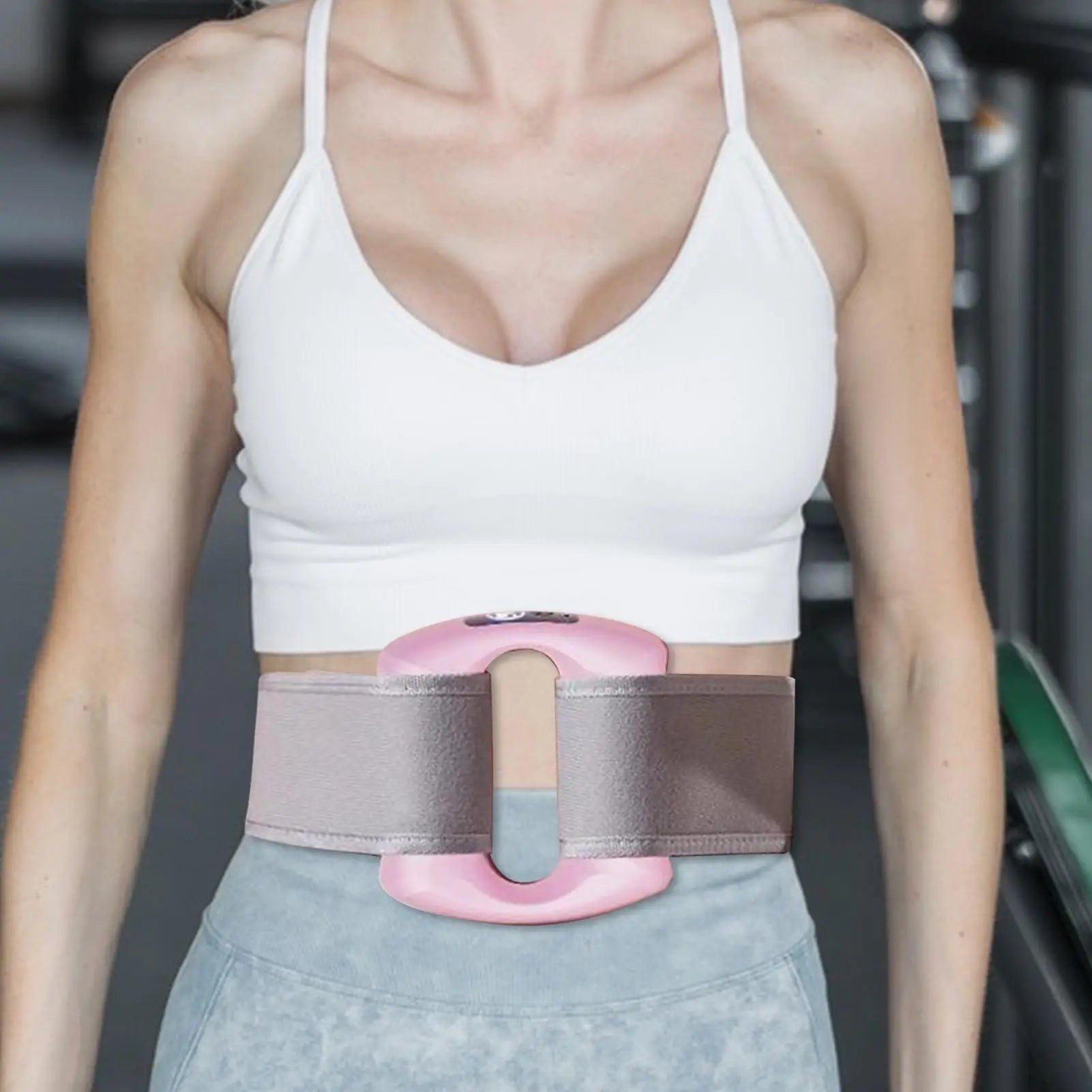 Person wearing a pink and gray waist trainer in a gym setting. مدلك الجسم