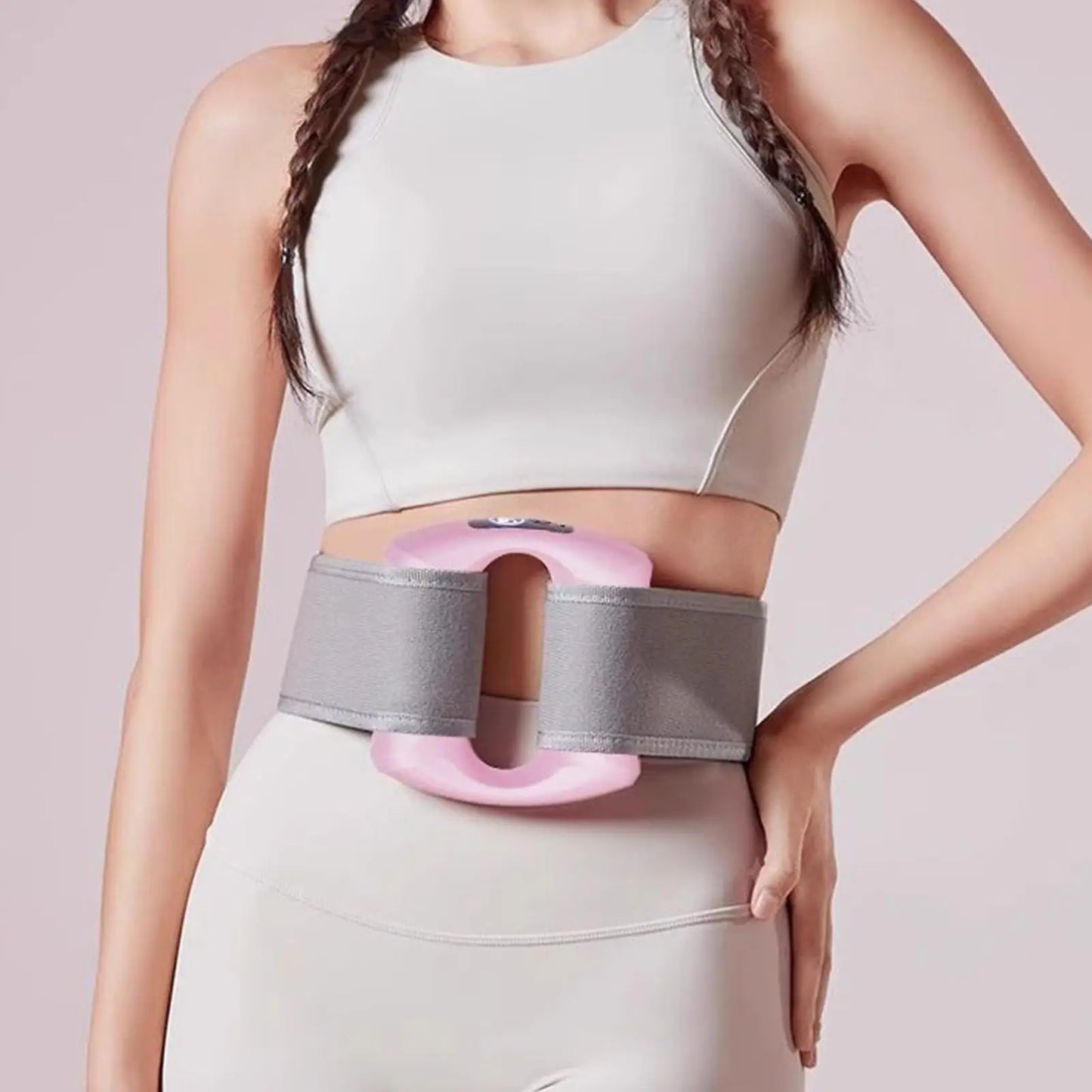 Person wearing a gray and pink waist trainer against a light background.مدلك الجسم